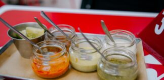 Sosy z kuchni świata, które odmienią codzienny obiad: od chimichurri po teriyaki Kolorowe sosy świata w szklanych słoiczkach z łyżeczkami na tacy
