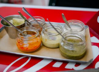 Sosy z kuchni świata, które odmienią codzienny obiad: od chimichurri po teriyaki Kolorowe sosy świata w szklanych słoiczkach z łyżeczkami na tacy