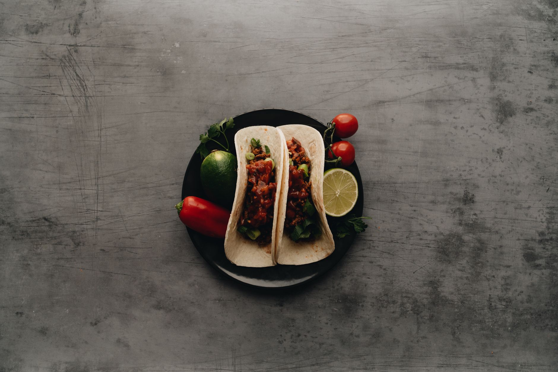 Tacos z pomidorkami koktajlowymi, limonką i pieprzem na talerzu