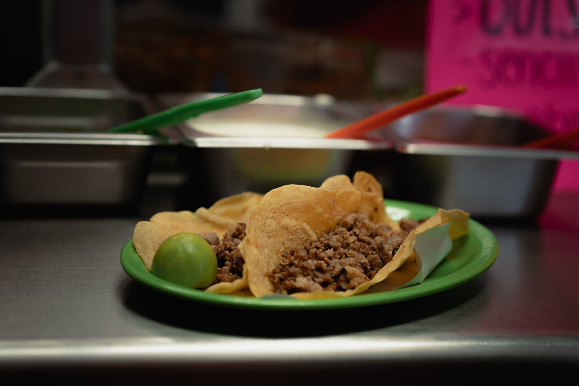 Zbliżenie na tacos z mięsem i limonką na zielonym talerzu w lokalu