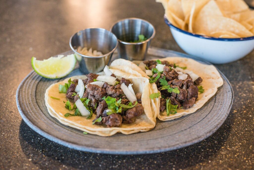 Zbliżenie na tacos z wołowiną, kolendrą i limonką na talerzu