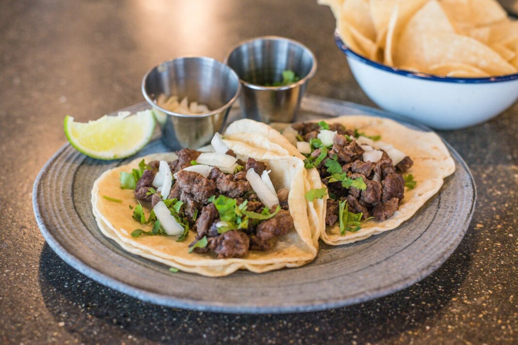 Zbliżenie na tacos z wołowiną, kolendrą i limonką na talerzu Zbliżenie na tacos z wołowiną, kolendrą i limonką na talerzu