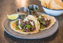 Zbliżenie na tacos z wołowiną, kolendrą i limonką na talerzu