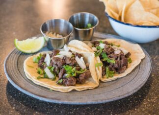 Zbliżenie na tacos z wołowiną, kolendrą i limonką na talerzu