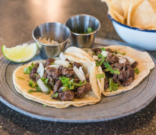 Sekrety kuchni meksykańskiej: taco, burrito i domowe tortille krok po kroku Zbliżenie na tacos z wołowiną, kolendrą i limonką na talerzu