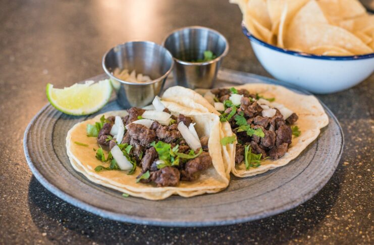 Zbliżenie na tacos z wołowiną, kolendrą i limonką na talerzu