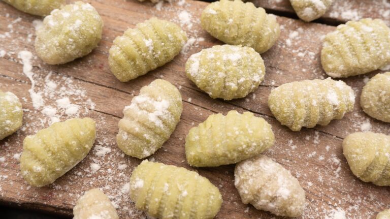 Zielone gnocchi oprószone mąką na rustykalnej drewnianej desce